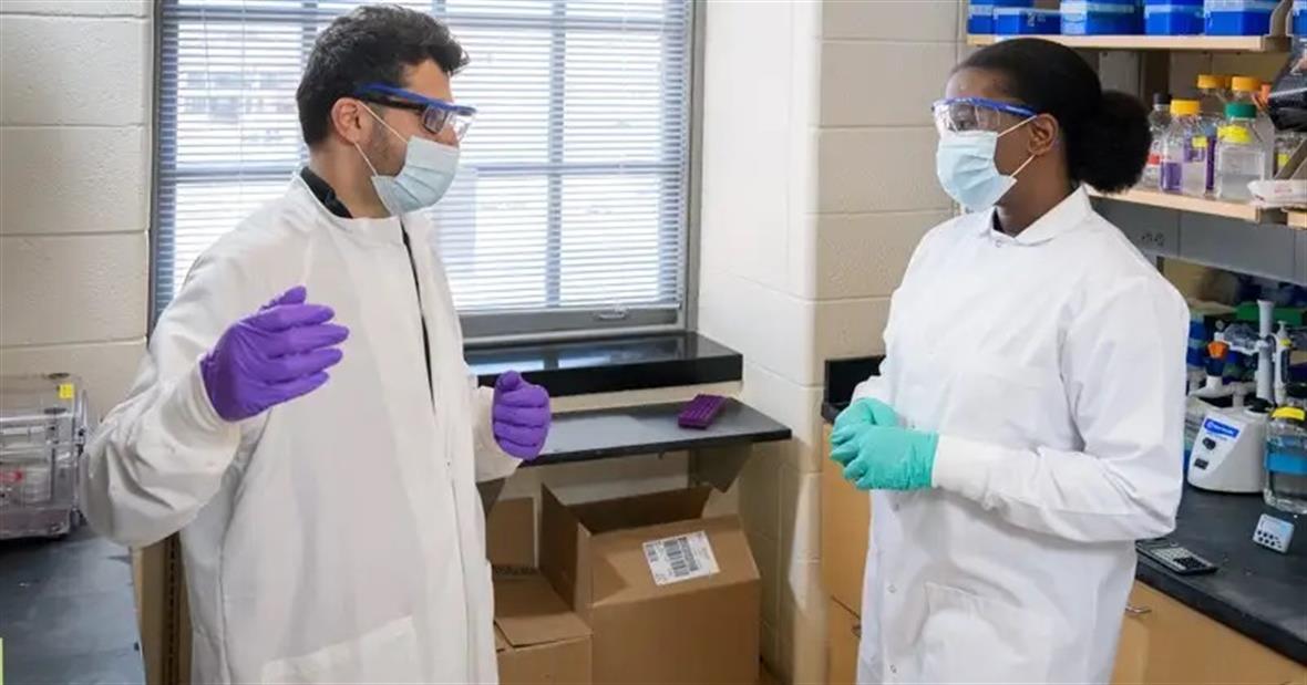 Doctoral students Sandeep Aryal (left) and Sarah Coomson discuss their research in the lab.